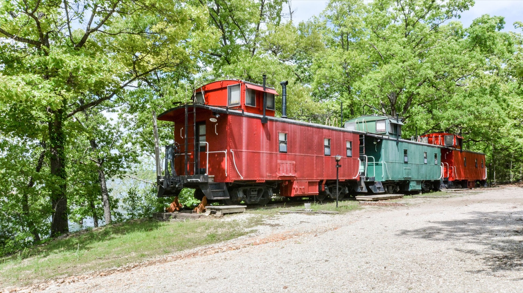 Three historic red and green cabooses at Caboose Junction Resort beside Table Rock Lake